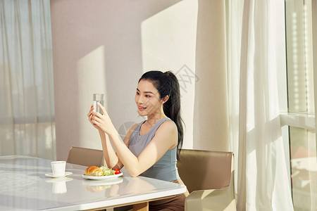 美女早晨坐在客厅享用早餐背景图片