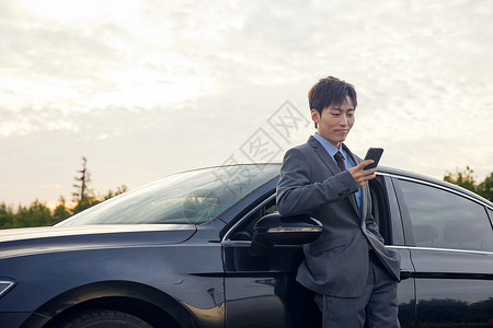 汽车在停车场站在车边休息看手机的商务男性背景