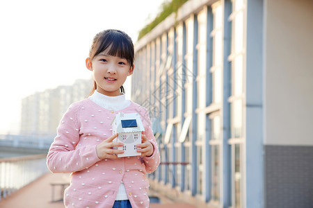 户外小女孩手拿太阳能房屋模型背景图片