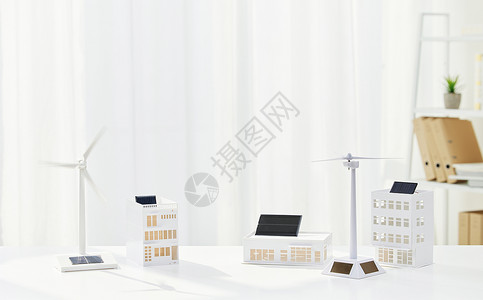新型节能灯泡桌上的风车和房屋模型背景