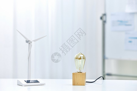 新型节能灯泡桌上的风力发电车和节能灯泡背景