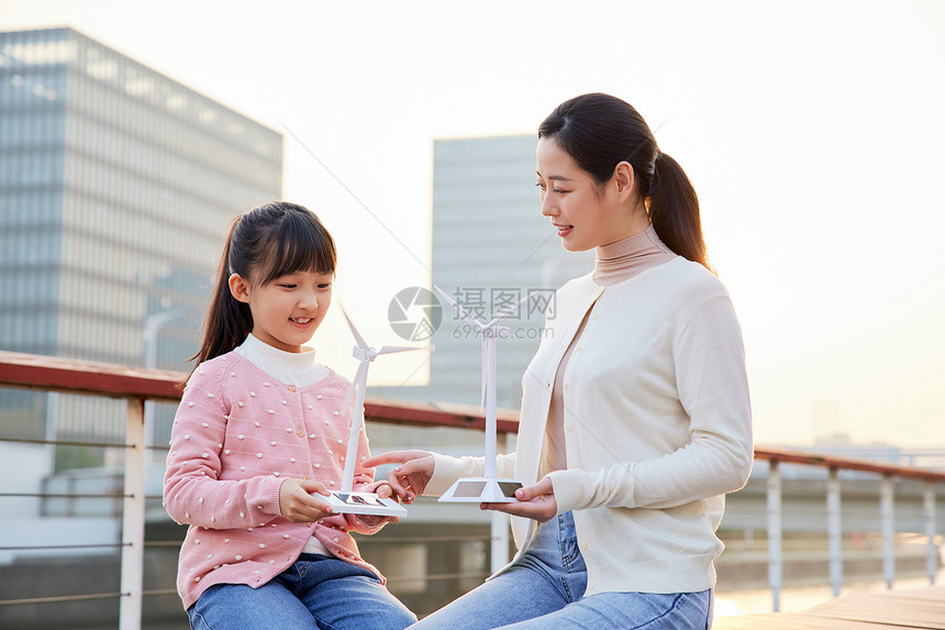 户外使用太阳能板给风车充电的母女图片