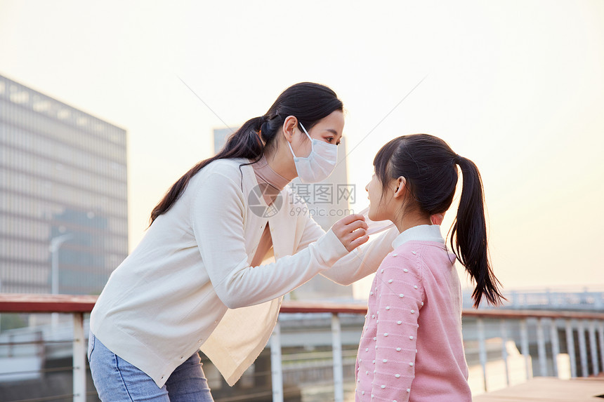 户外妈妈帮女儿戴口罩图片