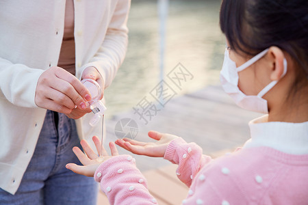 户外母女使用凝胶护手消毒特写图片