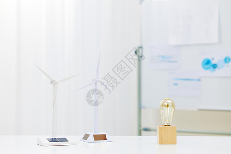 低碳办公办公桌上的风力发电车和节能灯泡背景