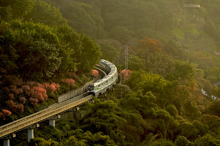 山城地貌夕阳下穿梭在山间的列车轻轨背景