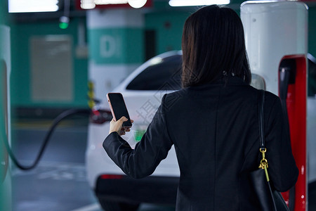 女性通过手机控制新能源汽车背影图片