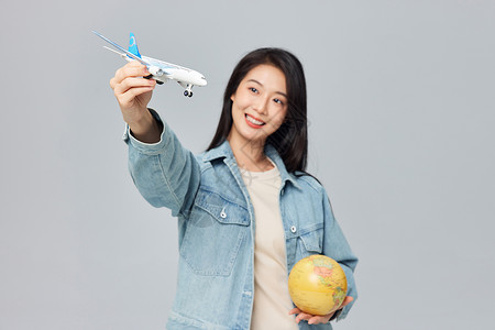 年轻女性手拿地球仪和飞机模型高清图片