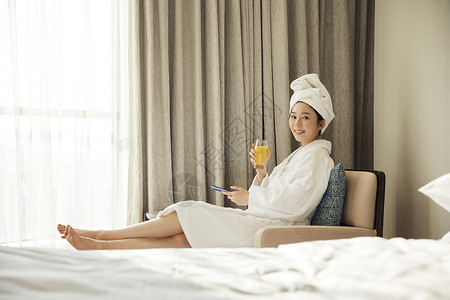 身穿浴袍的美女酒店休闲看手机喝橙汁图片