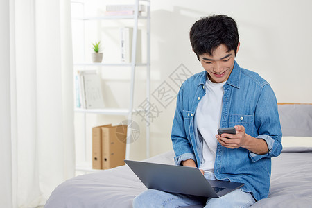年轻居家男青年使用电脑和手机高清图片