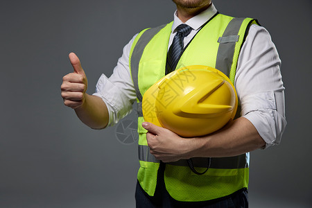 工程师拿图纸点赞建筑工人抱着安全帽点赞特写背景