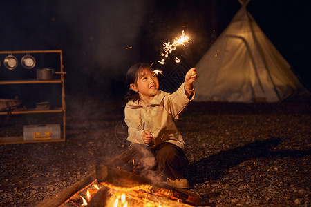 小女孩夜晚露营篝火放烟花图片