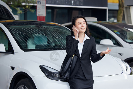 靠在新能源汽车旁打电话的商务女性高清图片