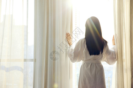 美女穿浴袍美女酒店早晨起床拉开窗帘背影背景