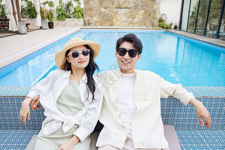 蜜月酒店泳池边戴太阳镜的年轻情侣背景