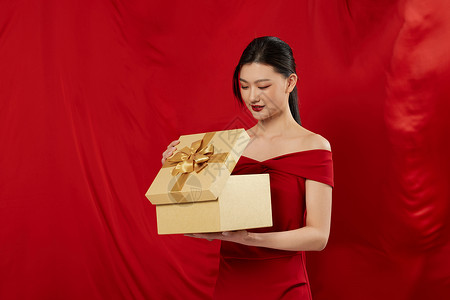 红衣女子打开手上的金色礼盒高清图片
