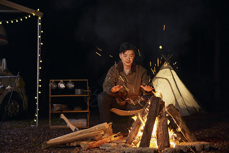 男青年夜晚户外露营篝火取暖图片