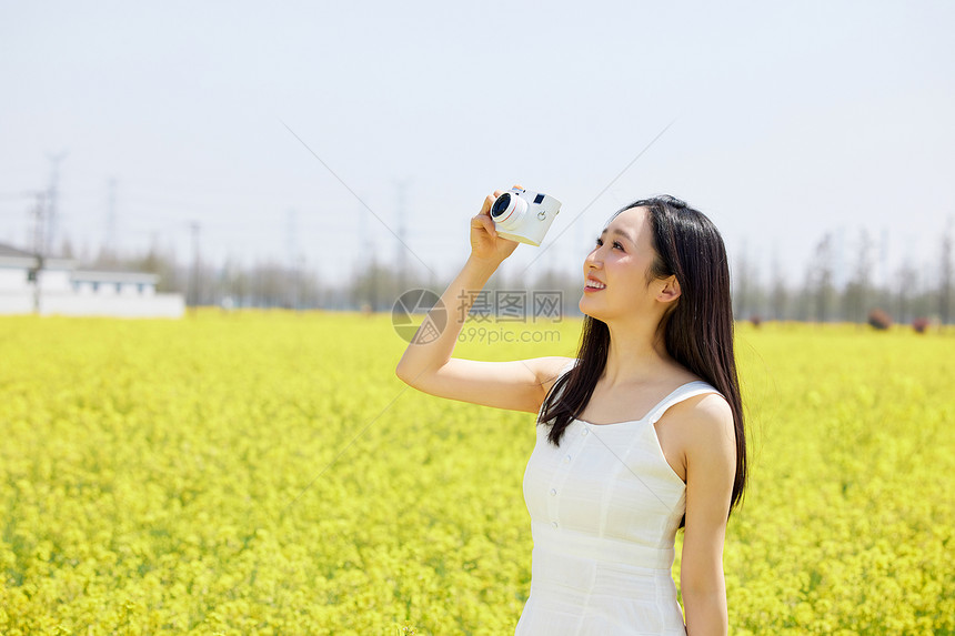 使用相机拍摄油菜花海的女性图片