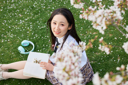 美女大学生旅行春游樱花树下少女看书背景
