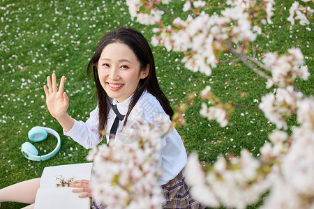 俯视视角樱花下的少女打招呼高清图片