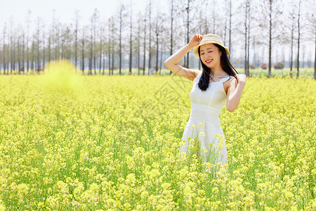 阳光朦胧女孩少女站在油菜花田里享受阳光背景