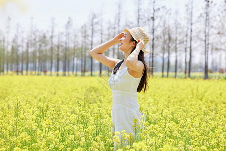 阳光朦胧女孩少女站在油菜花田享受阳光背景