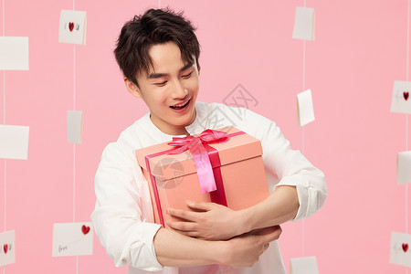 感谢贺卡礼品盒粉色背景抱着礼物的男生背景