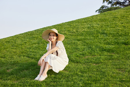 山坡小清新草地上晒太阳的青年女性背景