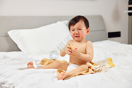 哭笑坐在床上哭闹的婴儿宝宝背景