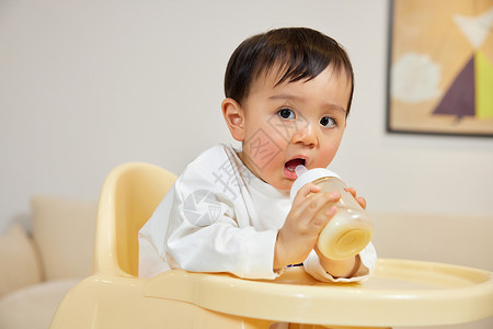 宝宝母乳坐在宝宝椅上手拿奶瓶的小宝宝背景