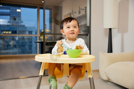 坐在宝宝椅上吃辅食的婴幼儿高清图片