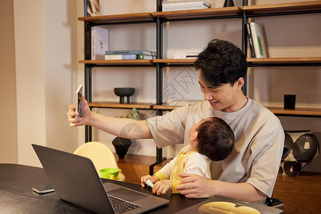 宝宝手机在书房和宝宝玩耍的年轻宝爸背景