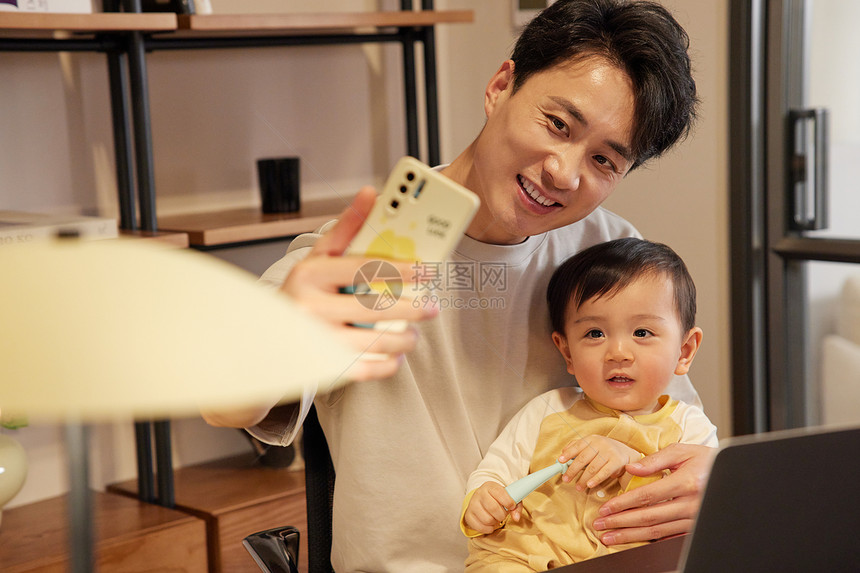 年轻爸爸使用手机和宝宝自拍合照图片