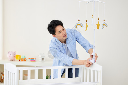 三角可爱挂签安装婴儿床挂饰的年轻奶爸背景