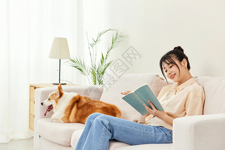 客厅里看书的青年女性和宠物柯基图片