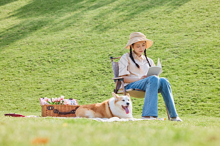 狗夏天公园里休闲看书的女主人和宠物狗背景