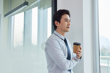 喝咖啡男士站在窗前喝咖啡的商务男士背景