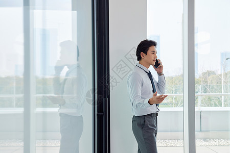 站在窗边打电话的商务男性高清图片