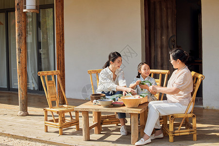 坐在粽子叶上三代人一起在院子里包粽子背景