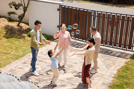 家人和睦一家五口在院子里玩游戏吹泡泡背景
