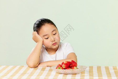 挑食的孩子小女孩看着草莓低落背景