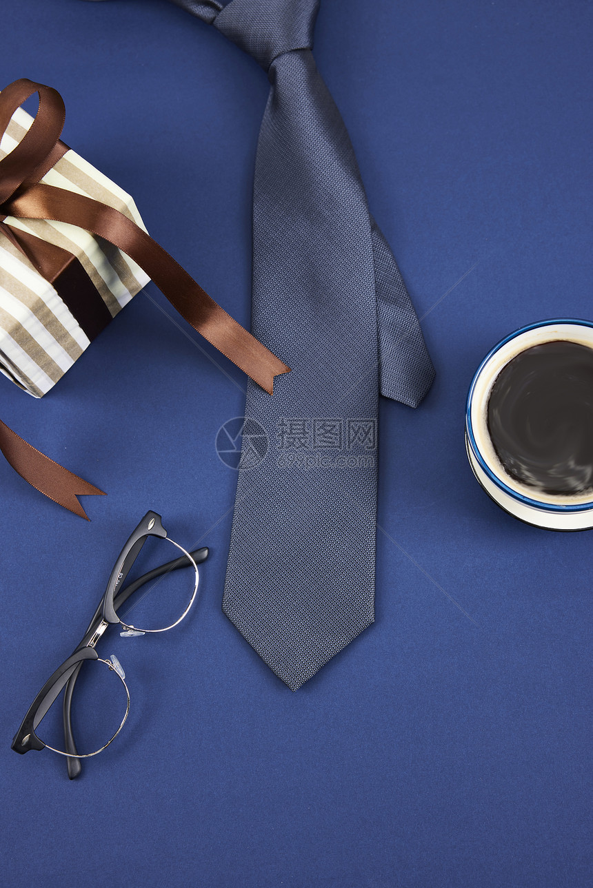 蓝色背景上放着领带和眼镜图片