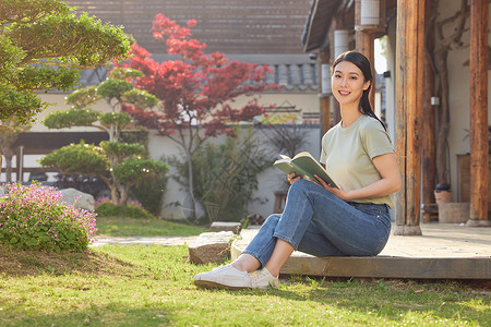 坐在院子里看书的女性背景图片