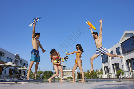 水枪派对快乐的年轻人们在泳池边打水仗背景