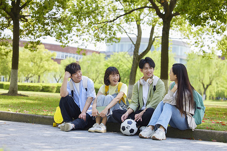 大学生们坐在校园草地边背景图片