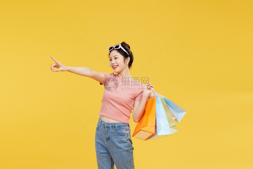 青年女性手提购物袋指向远方图片