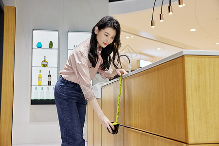 设计五金青年女性测量橱柜尺寸背景
