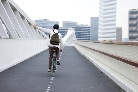户外骑自行车年轻男性都市骑自行车通勤背影背景