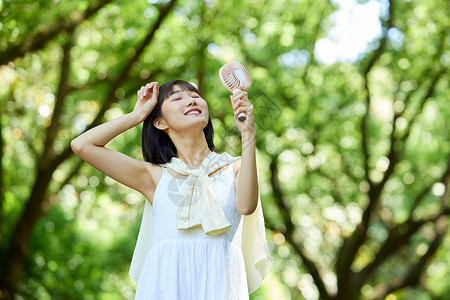 户外使用便携风扇的少女高清图片