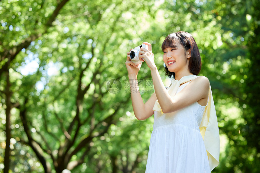 女生夏日外出散步用照相机拍照图片